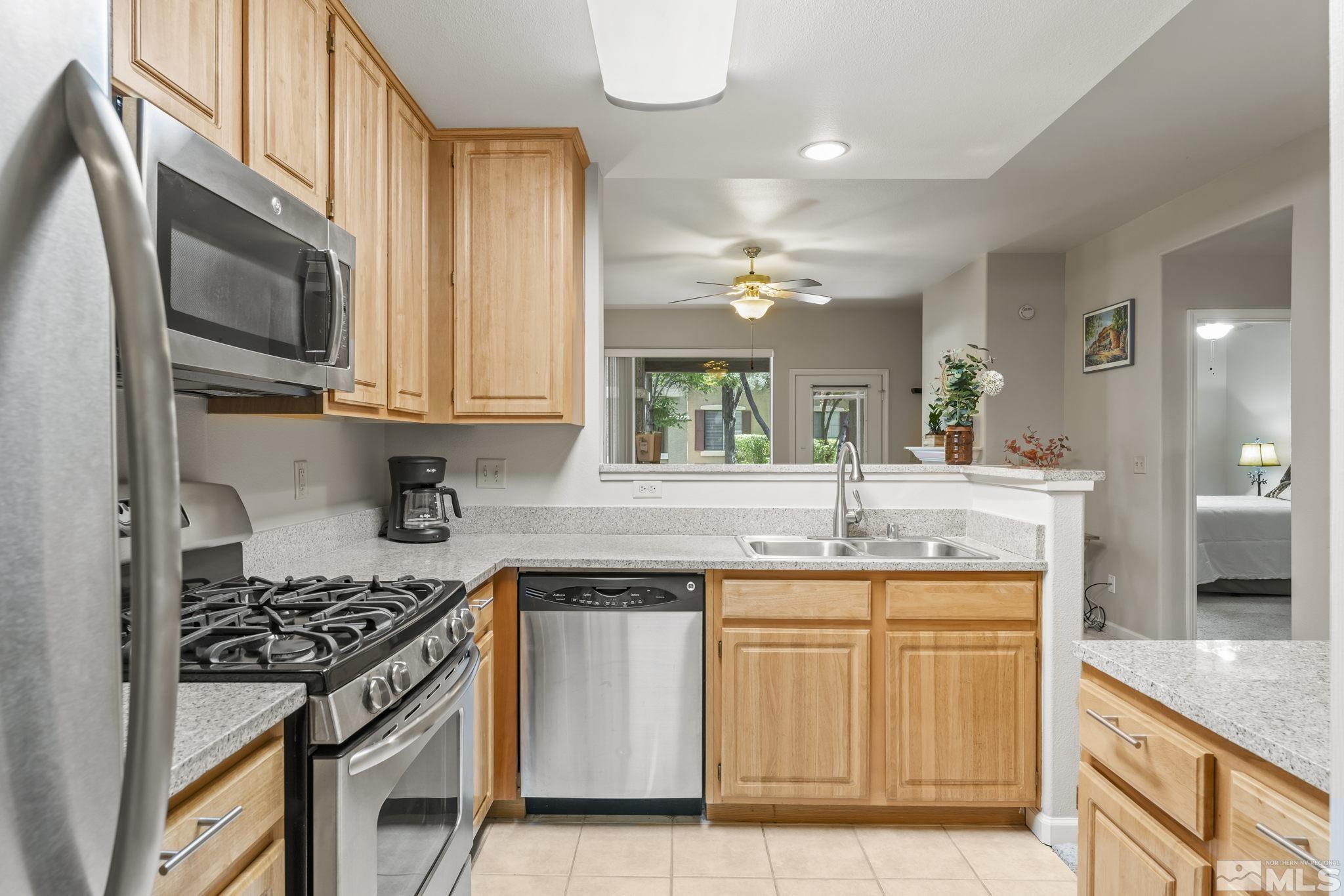 900 South Meadows Parkway, Unit 312 Reno, NV 89521 - Photo 7 of 38 a kitchen with stainless steel appliances granite countertop a stove a sink and a microwave