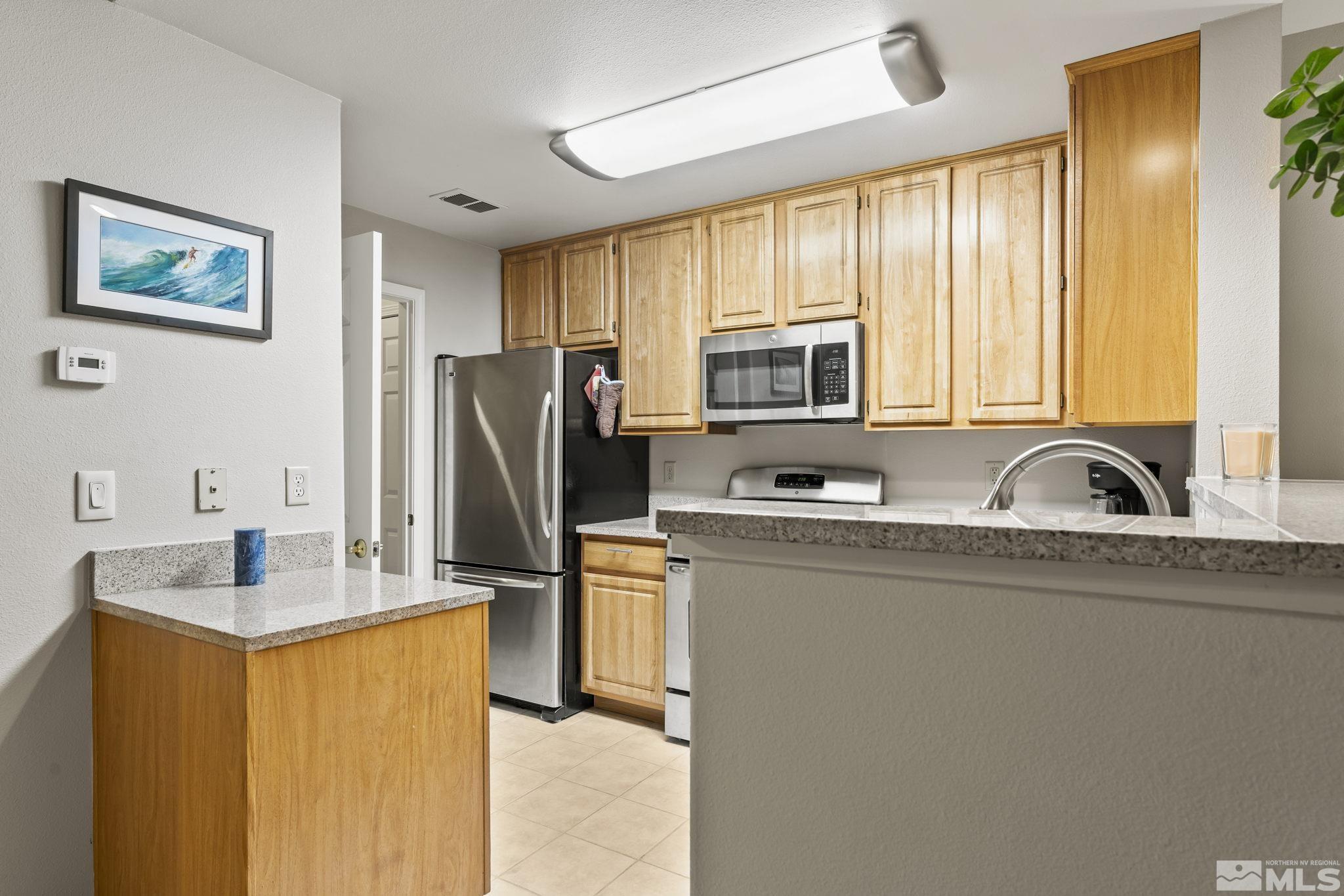 900 South Meadows Parkway, Unit 312 Reno, NV 89521 - Photo 8 of 38 a kitchen with stainless steel appliances granite countertop a refrigerator a sink a stove a microwave and cabinets