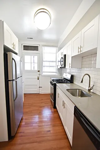 a kitchen with stainless steel appliances granite countertop a refrigerator sink and white cabinets