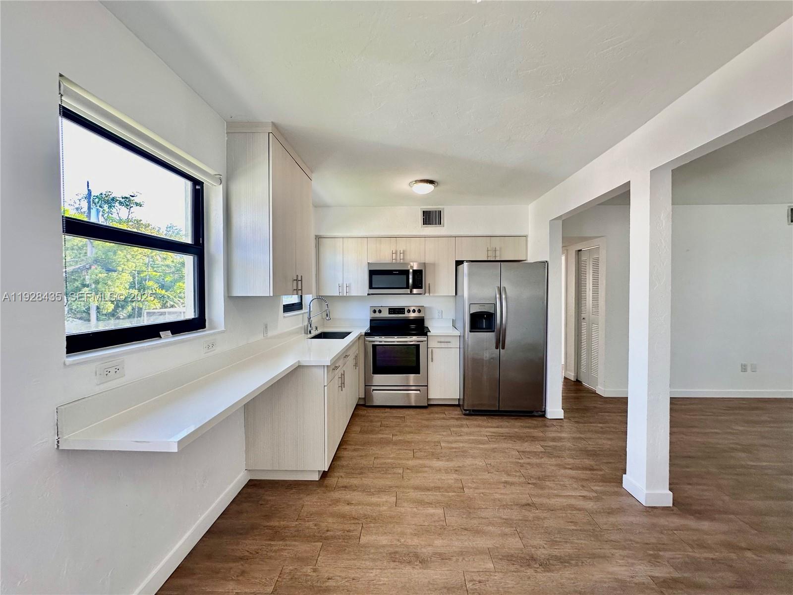 4204 Southwest 14th Street, Unit 3 Miami, FL 33134 - Photo 7 of 12 a large kitchen with stainless steel appliances a large counter top and a refrigerator