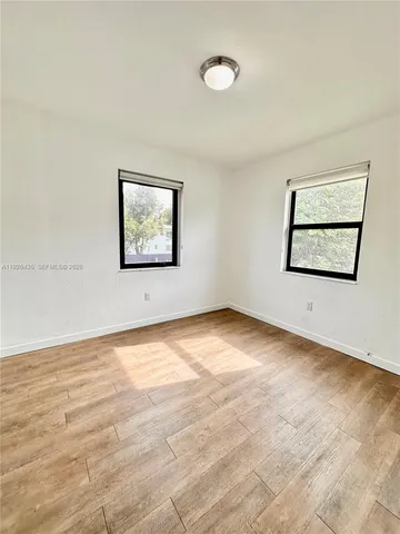 a view of an empty room with window and wooden floor