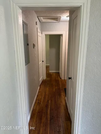 a view of a hallway with wooden floor and a bathroom