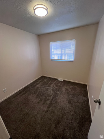 556 North Fairfield Road, Unit D4 Layton, UT 84041 - Photo 8 of 23 Empty room featuring a textured ceiling and dark carpet