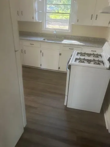 a kitchen with granite countertop white cabinets and white appliances