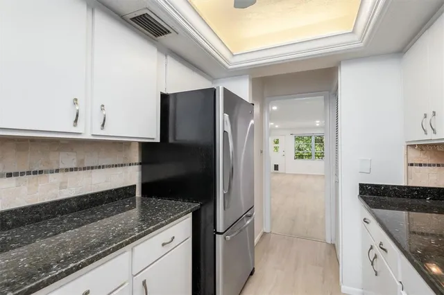 a kitchen with granite countertop a refrigerator and cabinets