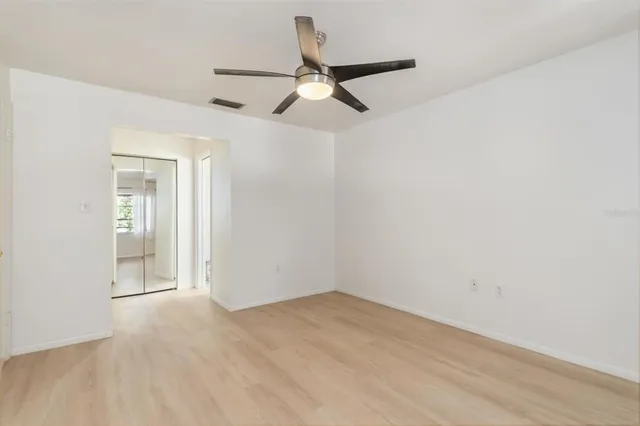 an empty room with a ceiling fan and wooden floor