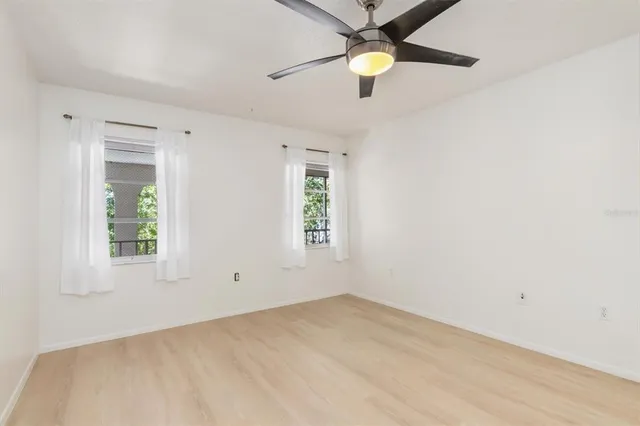 an empty room with windows and fan