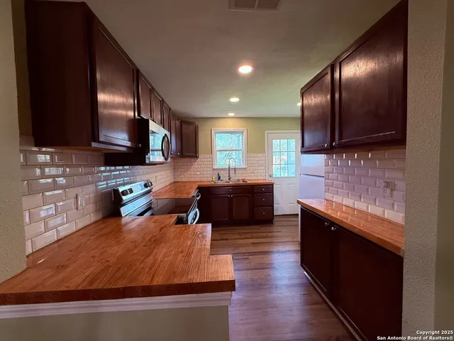 a kitchen with stainless steel appliances wooden cabinets a stove a sink and a microwave