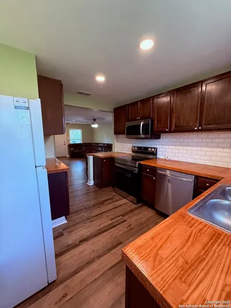 a kitchen with stainless steel appliances kitchen island granite countertop wooden cabinets a sink a stove a microwave and island