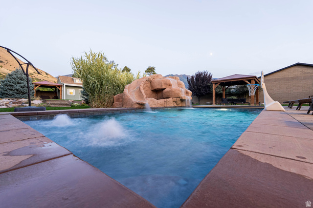 687 South 2080th Street East Springville, UT 84663 - Photo 138 of 149 Expansive swimming pool with a rock waterfall feature, integrated water jets, and a paved surround