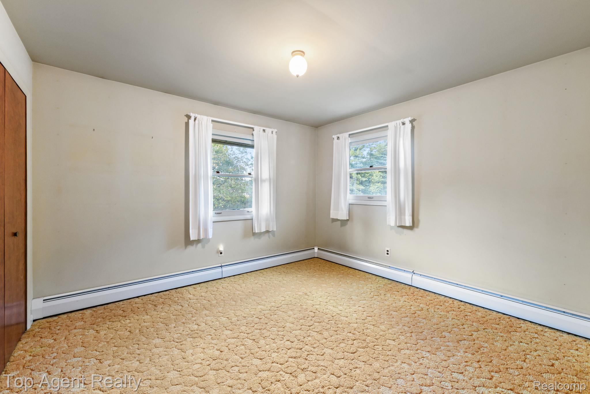8269 Currie Road Northville, MI 48168 - Photo 32 of 80 Built-in closet with wood-finish doors, two windows, wall-to-wall carpeting, and baseboard heating units