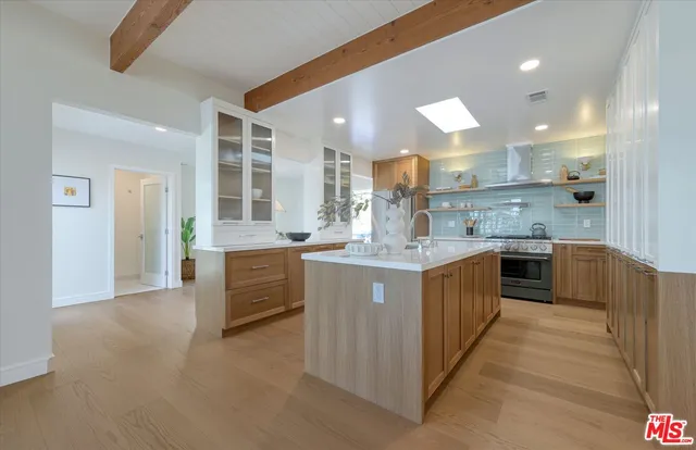 a large kitchen with a large counter top a sink stainless steel appliances and cabinets