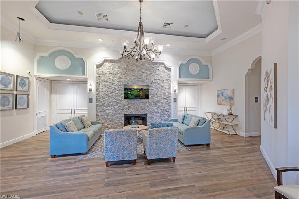 1411 Princess Sabal Point Naples, FL 34119 - Photo 30 of 31 Living area with arched walkways, light wood finished floors, hanging lights, a stone fireplace, and a high ceiling