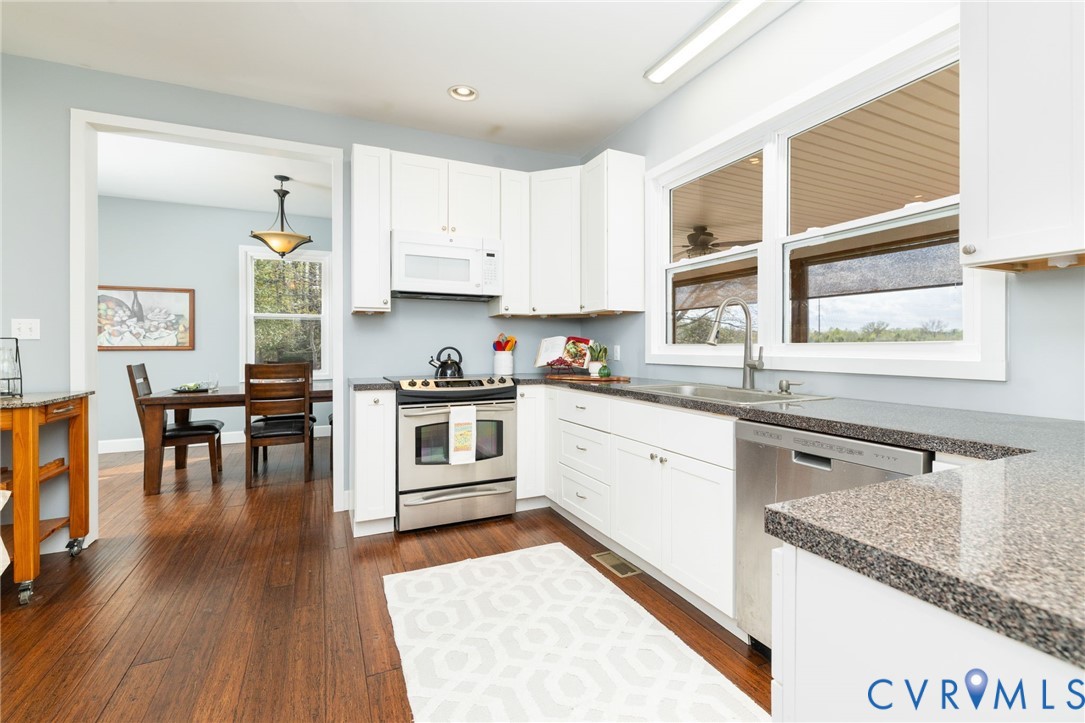 1895 Cemetery Road Chase City, VA 23924 - Photo 12 of 83 a kitchen with granite countertop a stove top oven a sink a dining table and chairs with wooden floor
