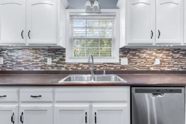 a kitchen with granite countertop white cabinets and a sink