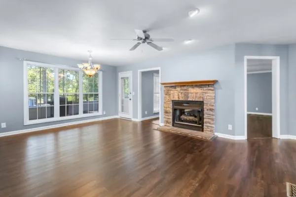 a view of an empty room with wooden floor fireplace and a window