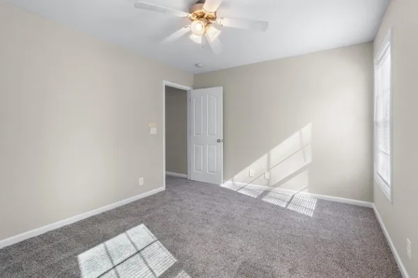 an empty room with a chandelier fan and windows