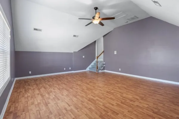 a view of a room with a wooden floor and a ceiling fan