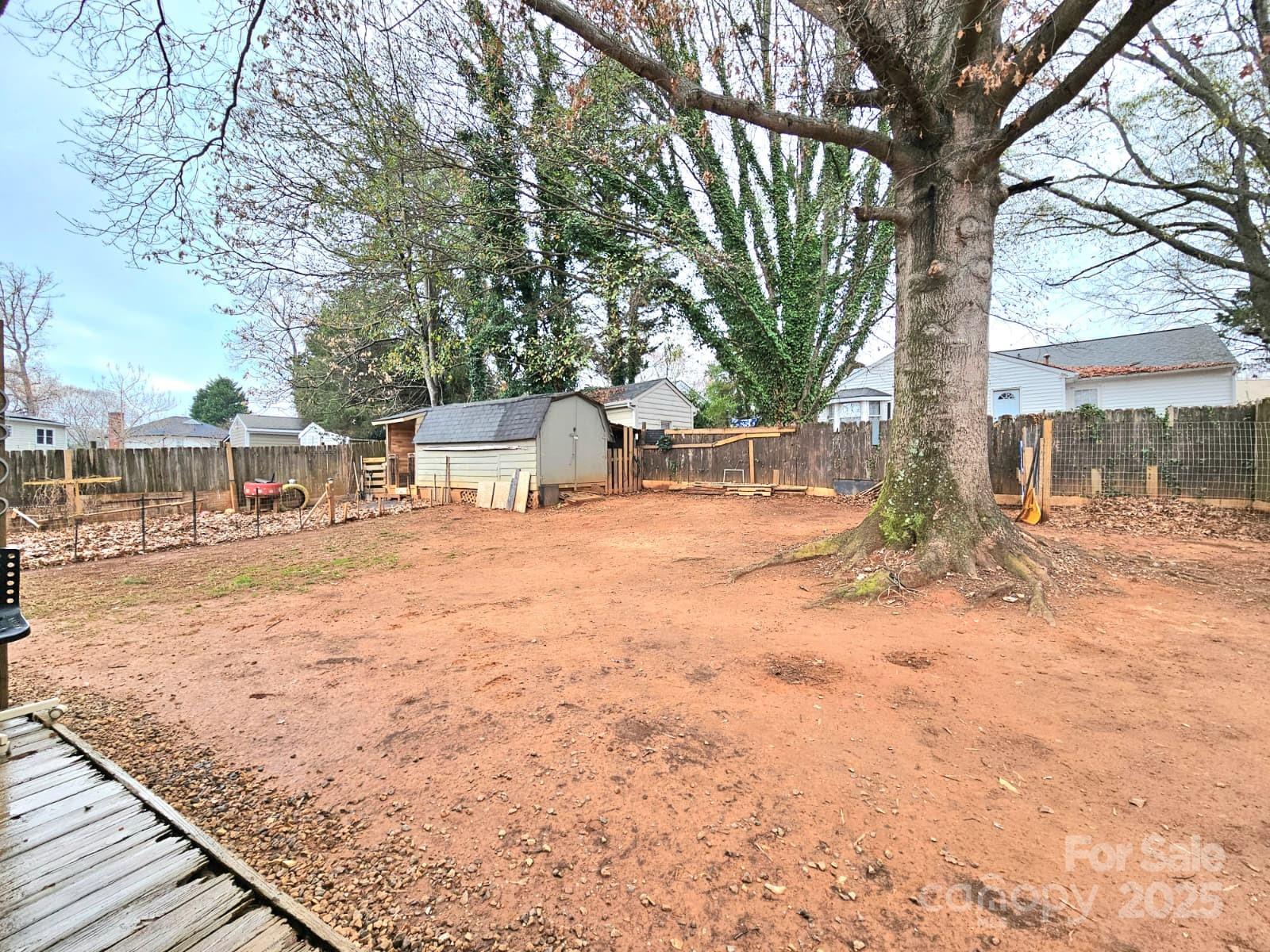 7344 Rena Mae Lane Charlotte, NC 28227 - Photo 16 of 19 a backyard of a house with large trees and covered with wooden fence
