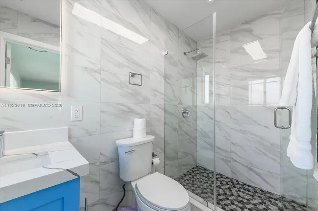 a white toilet sitting next to a bathroom sink and a shower