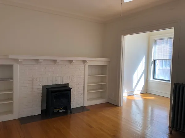 a view of an empty room with a fireplace and a window