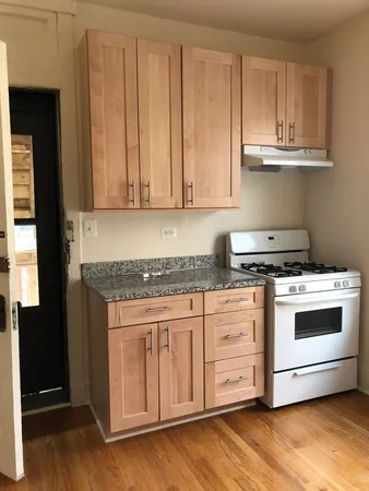 a kitchen with granite countertop white cabinets and a stove top oven