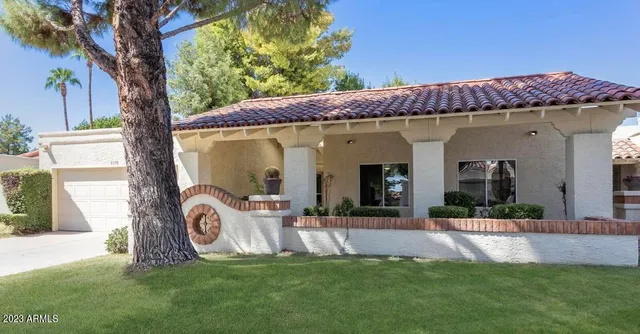 a view of a house with potted plants and a large tree