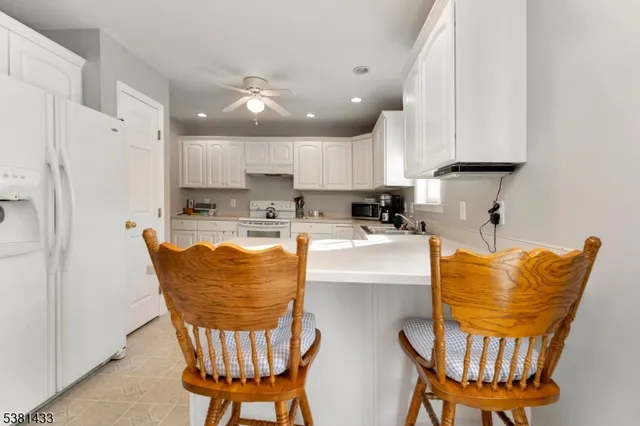 a kitchen with stainless steel appliances granite countertop a dining table chairs and a refrigerator