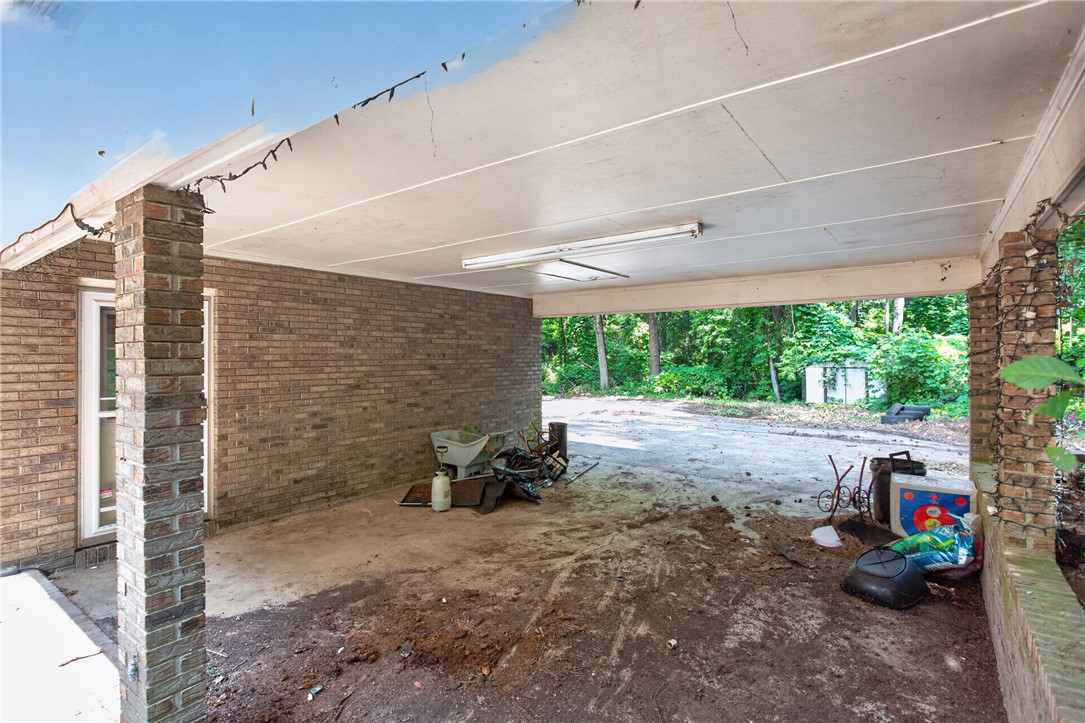 123 Robin Road Westminster, SC 29693 - Photo 8 of 50 A spacious covered carport offers shelter and direct access to a brick-clad home, framed by abundant greenery.
