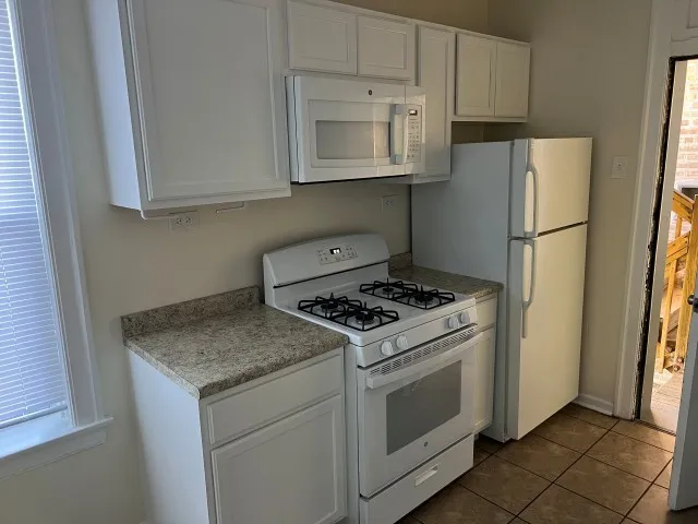 a kitchen with granite countertop white cabinets and white appliances