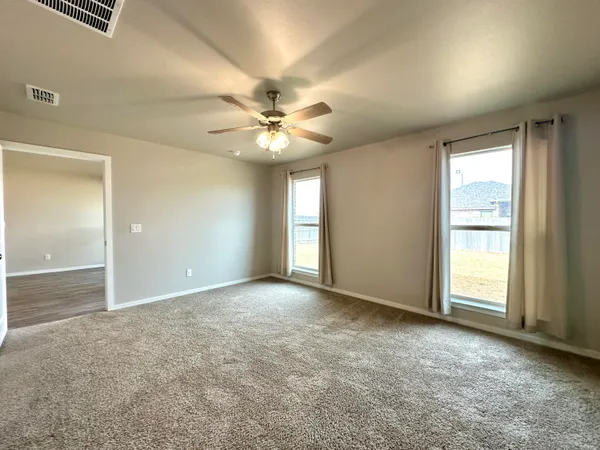 an empty room with windows and fan