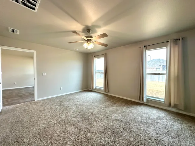 an empty room with windows and fan