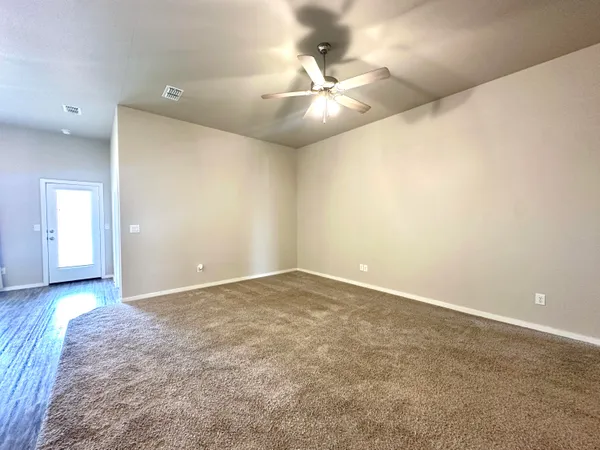 an empty room with a chandelier fan and windows