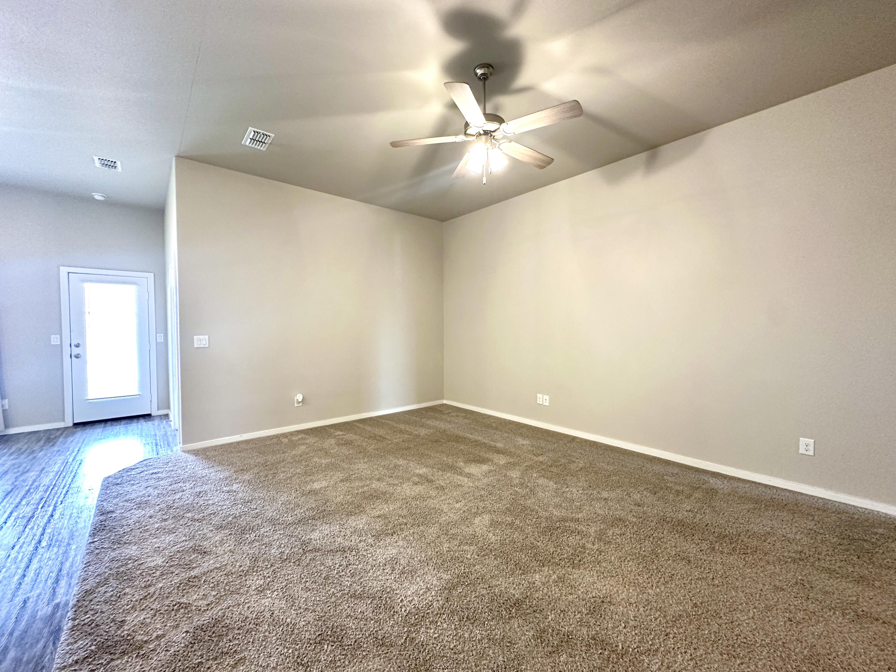 7526 31st Place Lubbock, TX 79407 - Photo 3 of 14 an empty room with a chandelier fan and windows