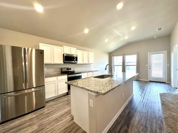 a kitchen with stainless steel appliances granite countertop a refrigerator a stove top oven a sink dishwasher and wooden floor