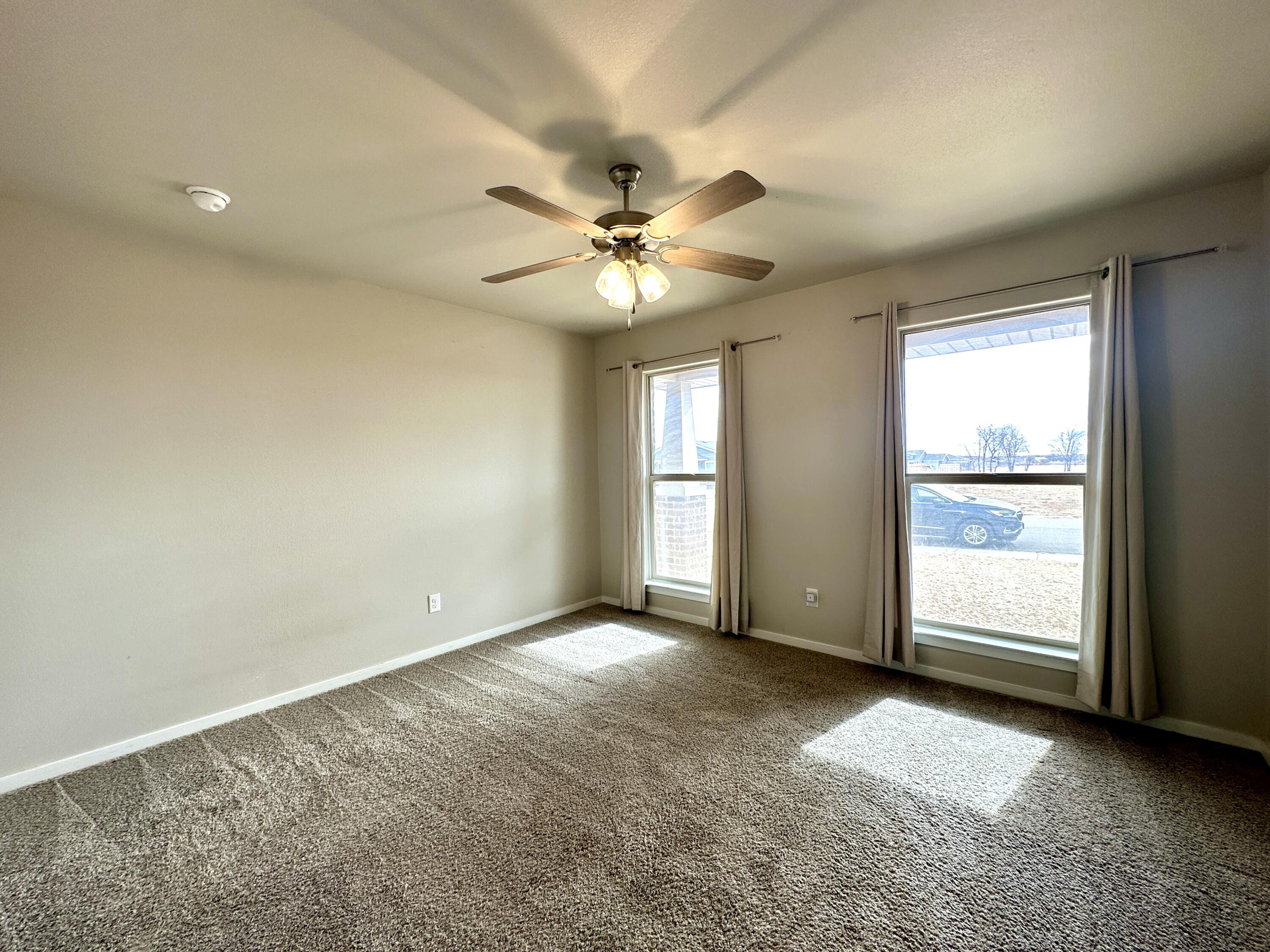 7526 31st Place Lubbock, TX 79407 - Photo 8 of 14 an empty room with chandelier fan and windows
