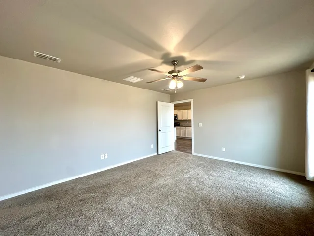 a view of an empty room with a chandelier fan
