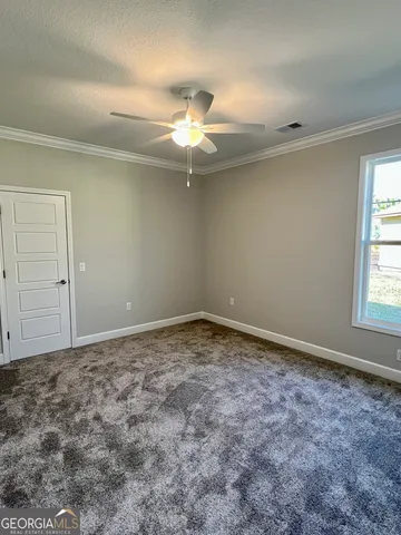 an empty room with a chandelier fan and windows