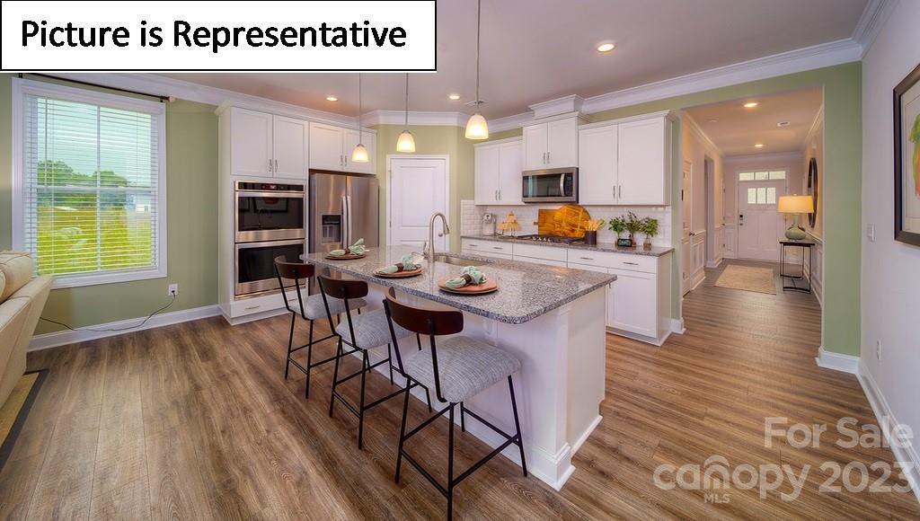 4182 Millstream Road Denver, NC 28037 - Photo 13 of 29 a kitchen with stainless steel appliances granite countertop a refrigerator a stove top oven a dining table and chairs with wooden floor