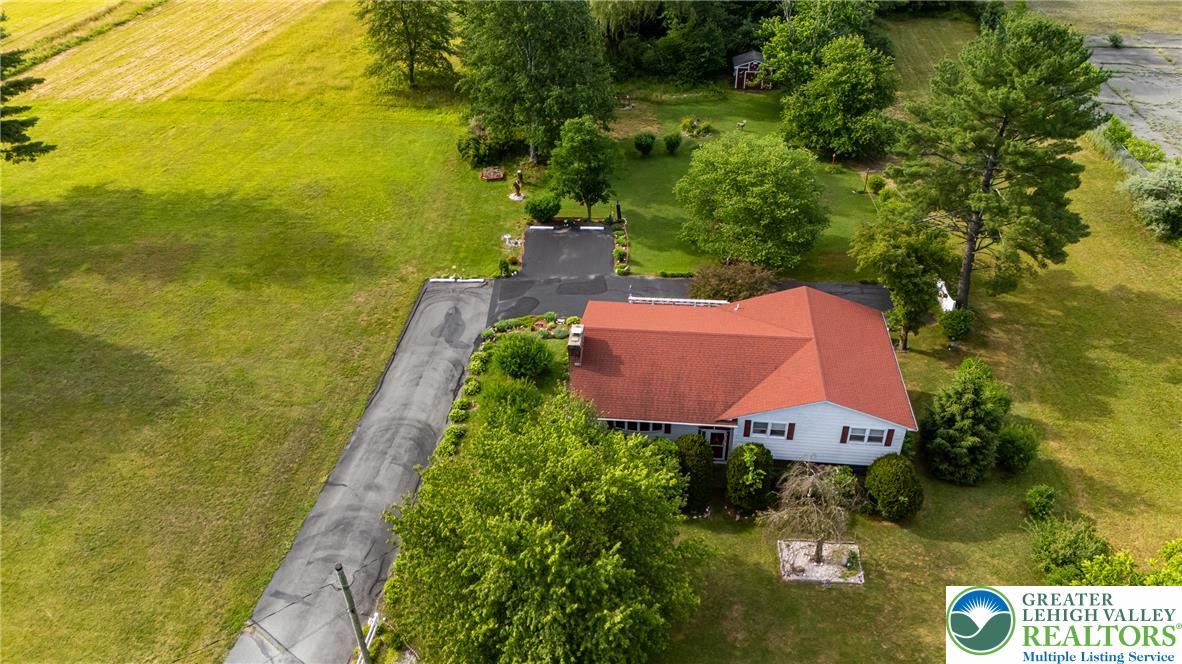 678 Interchange Road Kresgeville, PA 18333 - Photo 8 of 45 An aerial perspective reveals a charming single-family home with a striking red roof nestled amidst lush, expansive green spaces.