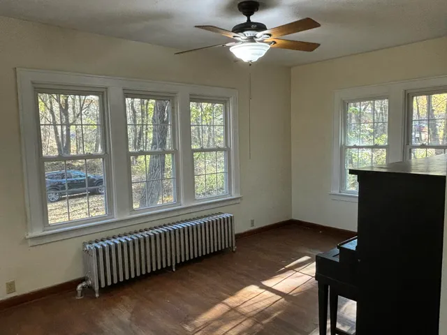 a view of an empty room with a window and wooden floor