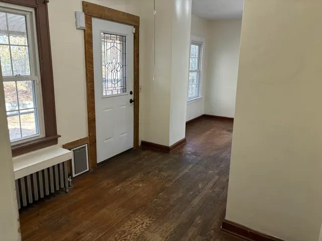 an empty room with wooden floor windows and hallway