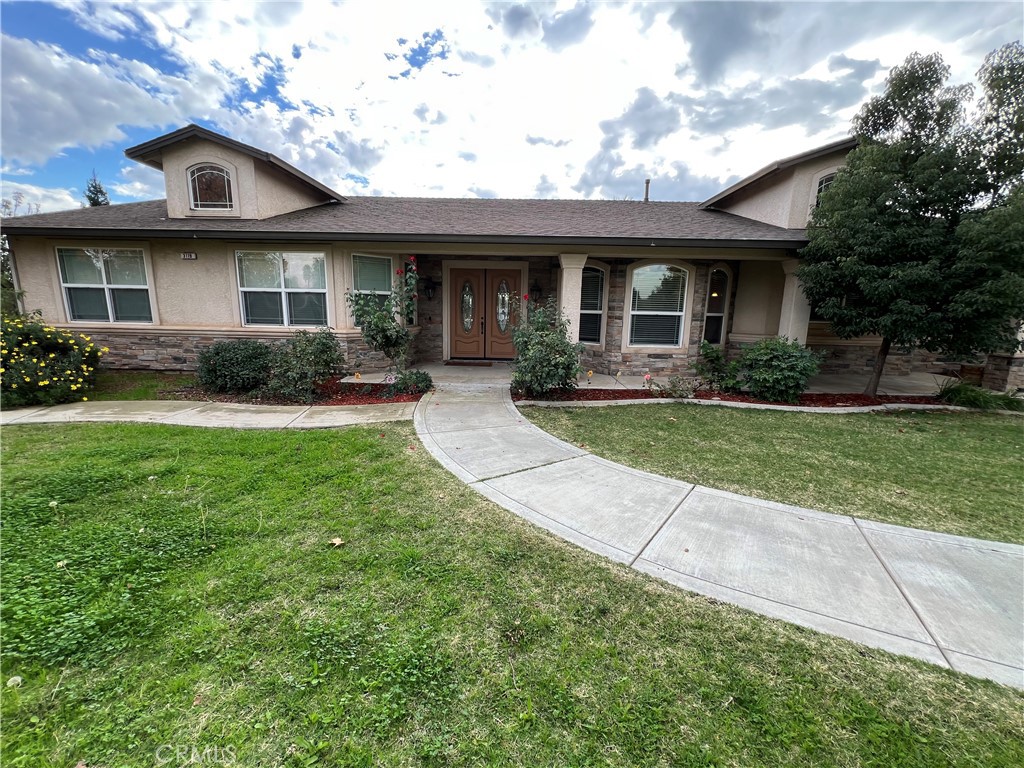 a view of a brick house with a big yard plants and large trees