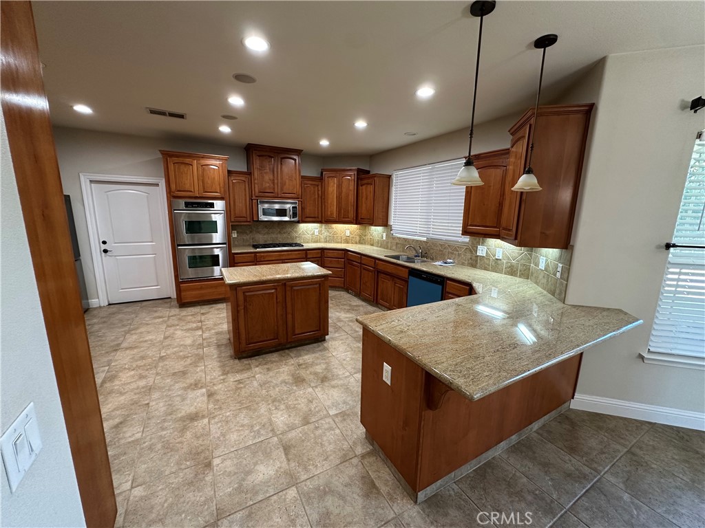 3119 Lorrie Court Merced, CA 95348 - Photo 11 of 38 a kitchen with kitchen island granite countertop a sink and a refrigerator