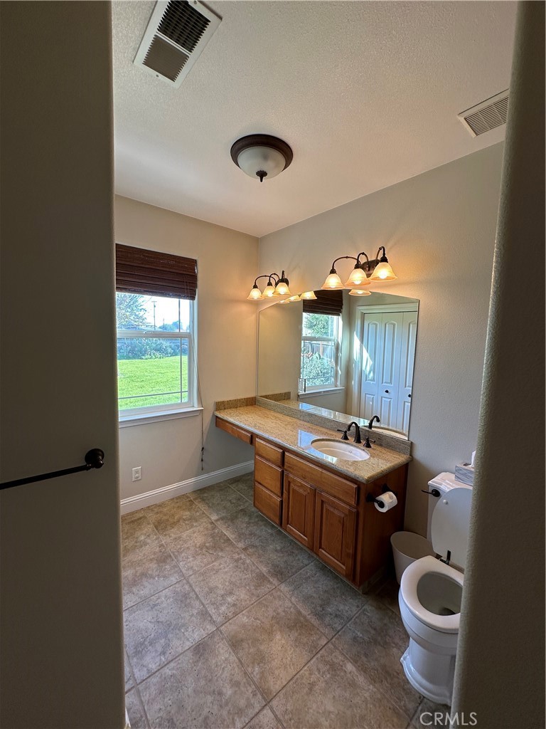 3119 Lorrie Court Merced, CA 95348 - Photo 21 of 38 a bathroom with a granite countertop sink a toilet and mirror