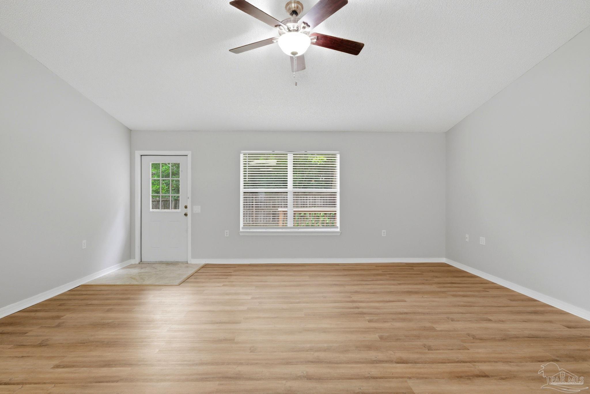 10120 Crest Ridge Drive Pensacola, FL 32514 - Photo 14 of 38 an empty room with wooden floor chandelier fan and windows