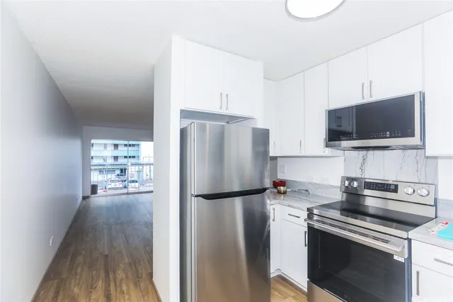 a kitchen with a refrigerator stove and wooden floor