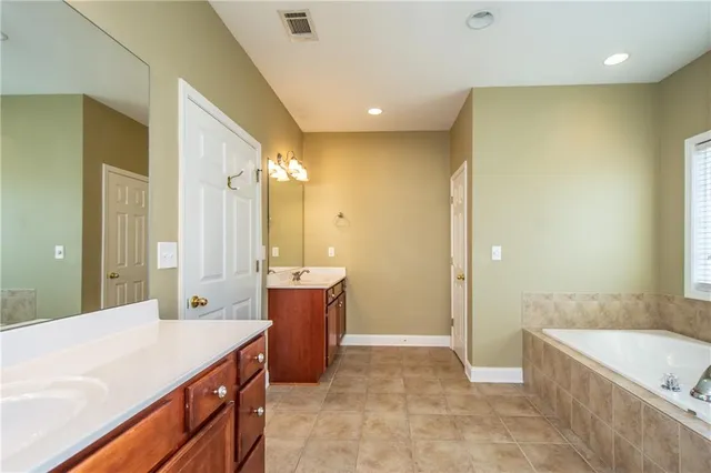 a bathroom with a granite countertop sink a bathtub a mirror and a shower