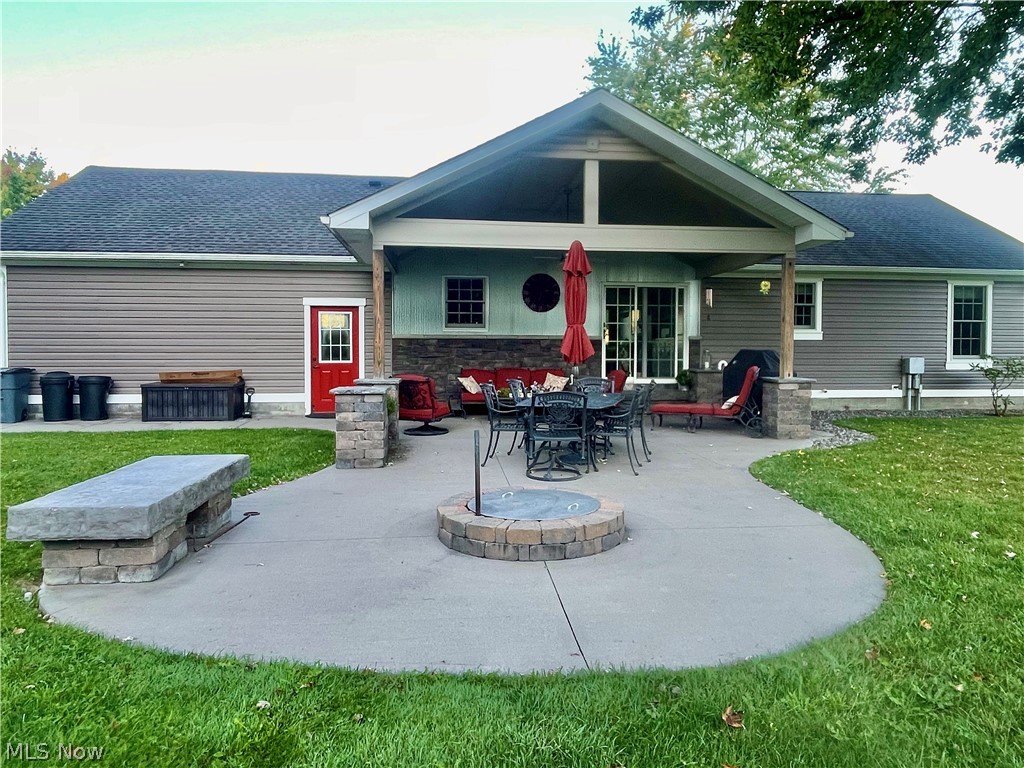 6120 Ridge Road Cortland, OH 44410 - Photo 10 of 42 Rear view of house with a patio, a shingled roof, a yard, outdoor dining space, and stone siding