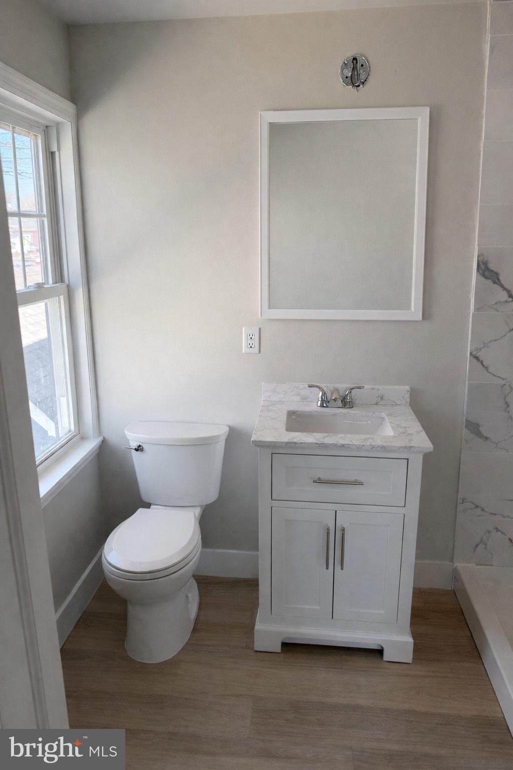 166 East Avenue, Unit F Pitman, NJ 08071 - Photo 3 of 4 a bathroom with a granite countertop toilet a sink and a mirror